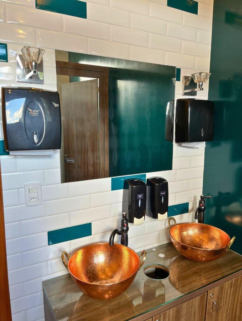 Lavabos do Galeto Piccolo Pollo em Nova Petrópolis, banheiro limpo com cubas de cobre e acabamento moderno.